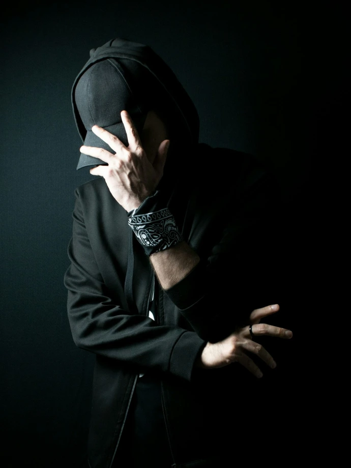 a man in a black hoodie covering his face with his hands